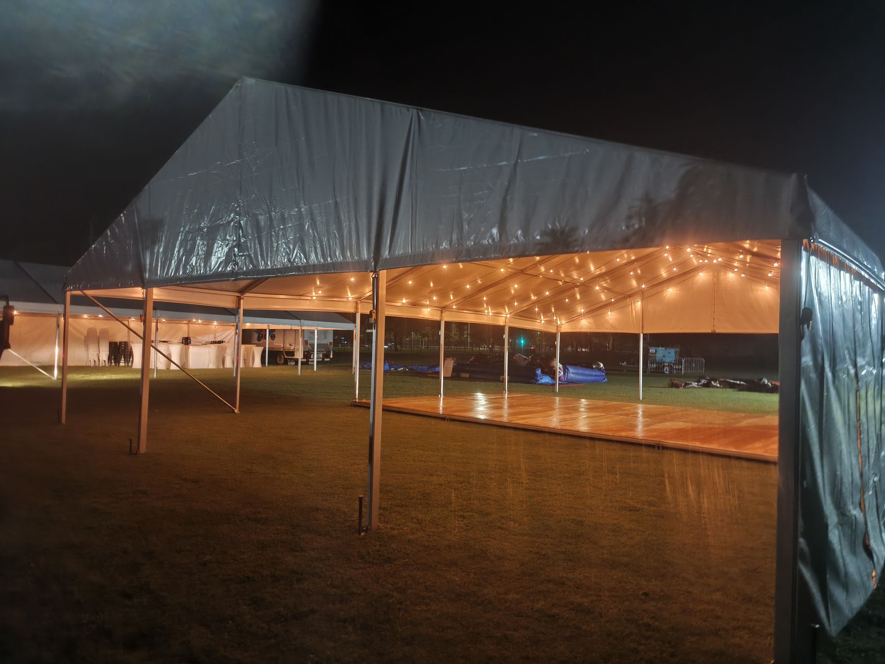 Structure marquee lit with festoon lights at night on a lawn