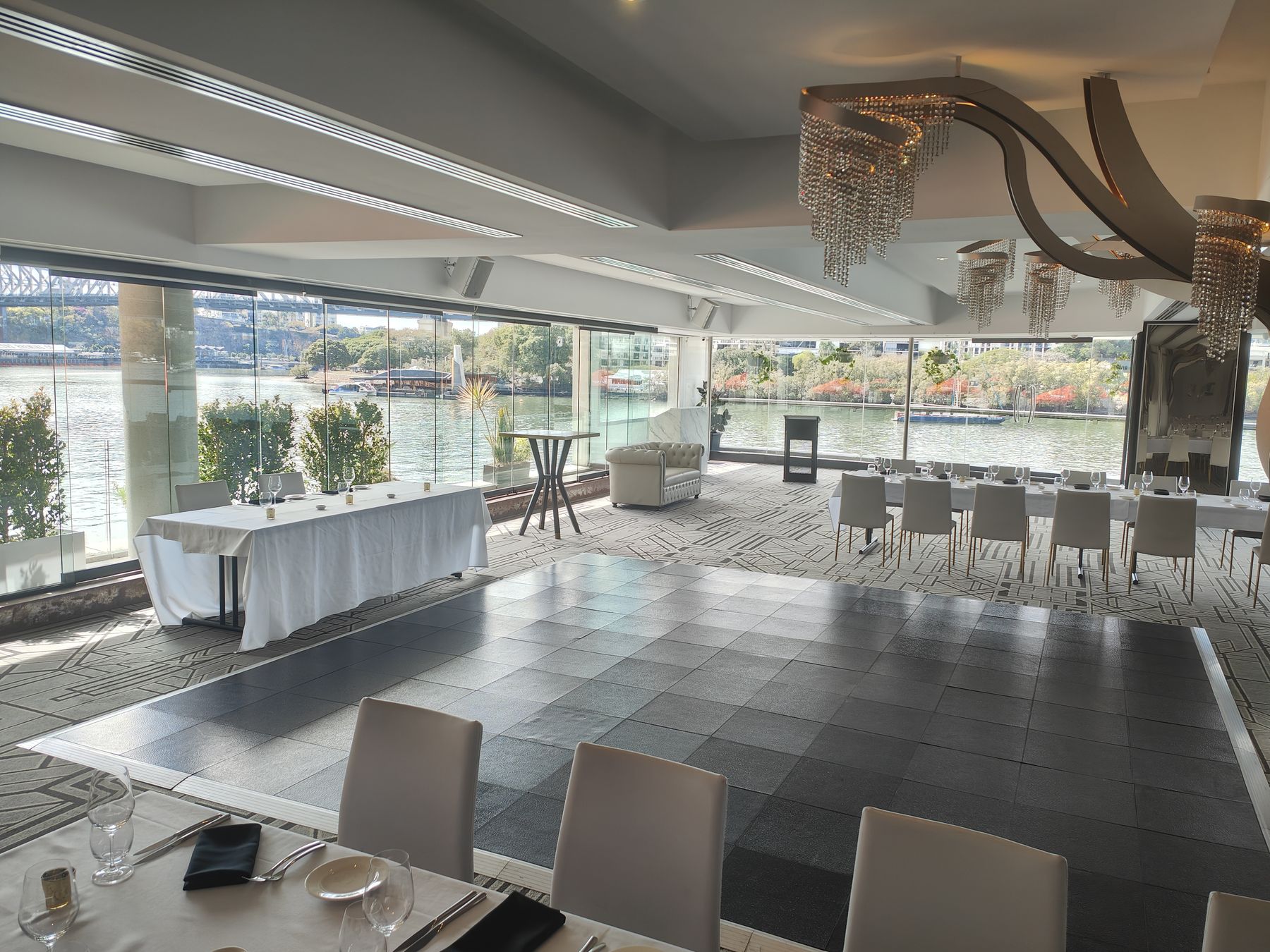 Function room with a white linen table and dining chairs beside a river window
